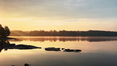 Pan-of-golden-hour-sunrise-over-lake,-Hällingsjö,-Sweden