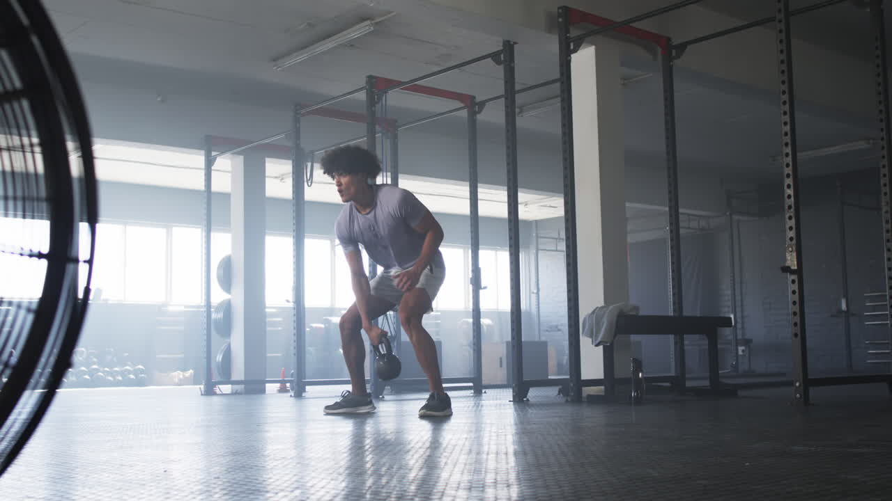 Lifting kettlebell, man exercising in gym with determination and focus