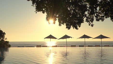 golden sunlight shines across the sky, sea and swimming pool of a luxury tropical resort holiday destination