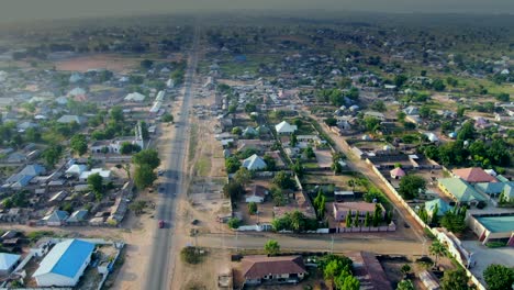 The-main-road-through-Damsa-Community,-Nigeria---aerial-pull-back-reveal
