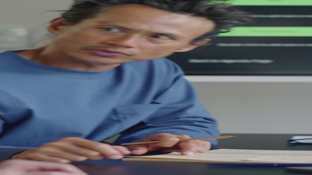 Hombre asiático hablando con un compañero en una mesa de reuniones