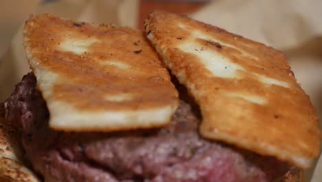 sliced and grilled halloumi cheese is placed atop a gourmet hamburger