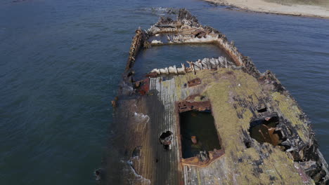 ships graveyard. a pass along the hull of derelict partially submerged shipwreck in the afternoon. aerial dolly shot.