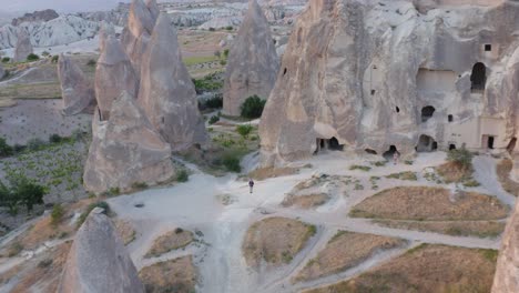 man flying through fairy chimneys towards traditional rock church in cappadocia turkey