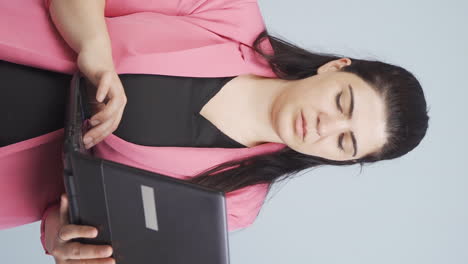 Vertical-video-of-Business-woman-looking-at-laptop-with-tired-expression.