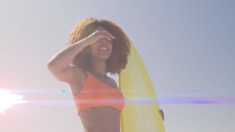 Animation-Von-Lichtern-über-Einer-Afroamerikanischen-Frau,-Die-Ein-Surfbrett-Hält