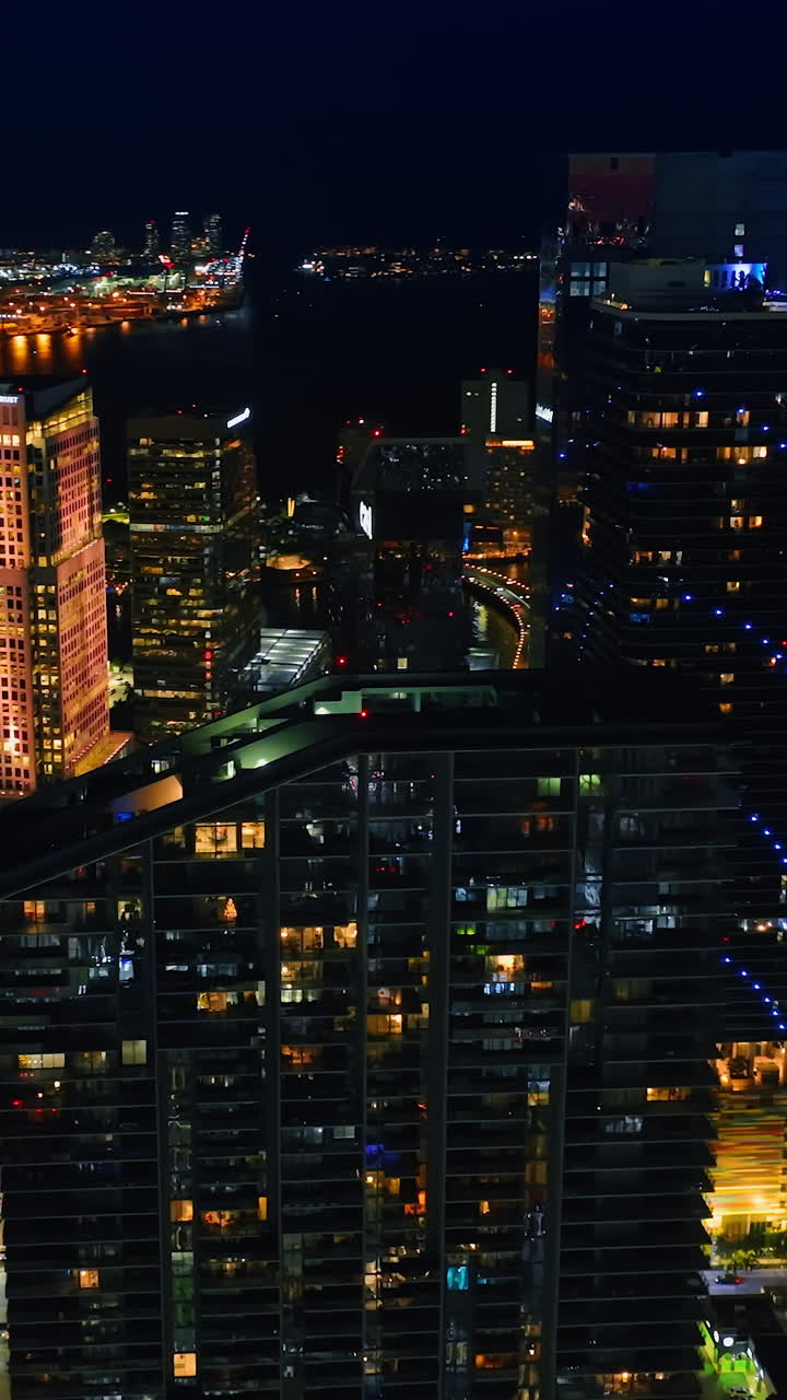 Drone flying around the wonderful skyscrapers at night. Gorgeous view of Miami, Florida, USA. Vertical video