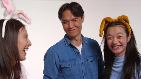 Group-Of-Young-Friends-In-Front-Of-White-Studio-Background-Having-Fun-Posing-For-Photo-Booth-Style-Portraits-With-Fake-Animal-Ears