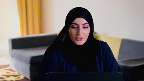 woman in hijab abaya calling through smart mobile cellular phone while working remotely