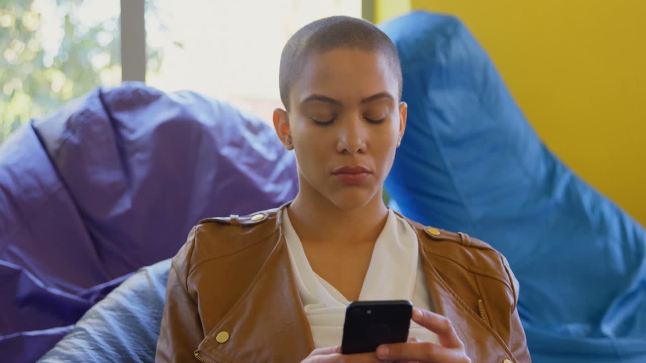 vista frontal de una joven ejecutiva caucásica usando un teléfono móvil en una oficina moderna 4k
