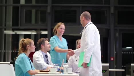 doctor shaking hands and interacting with colleagues in conference room