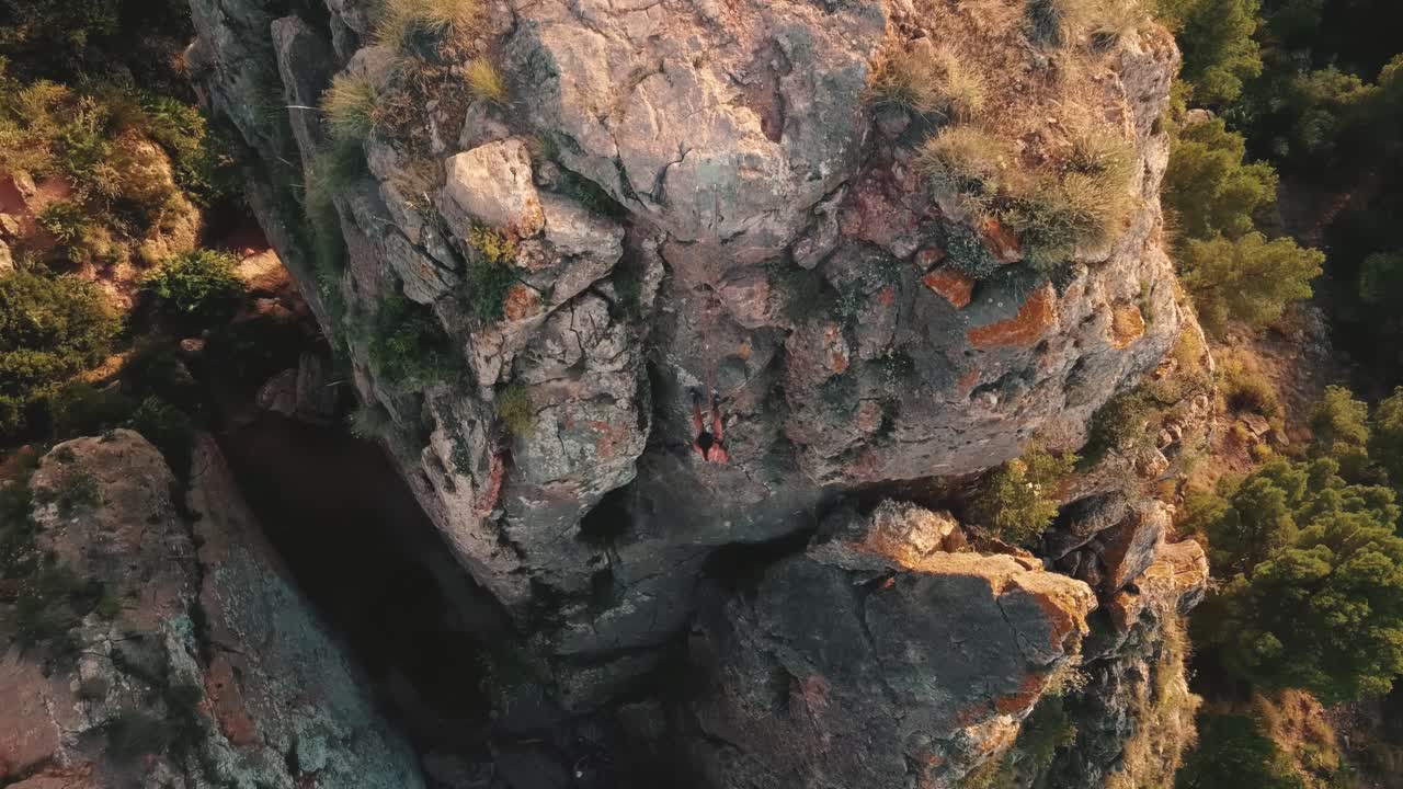 Aerial view of woman rapel down a mountain climbing a big rock