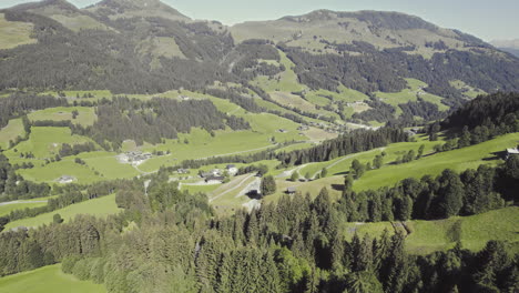 Aerial-over-picturesque-tyrolean-countryside-with-forest-covered-mountains-and-grassy-fields-3