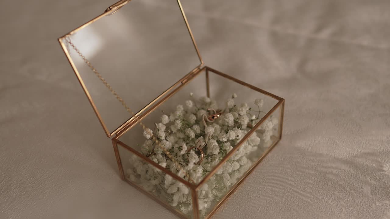 Close up of wedding rings placed in a glass box with baby’s breath