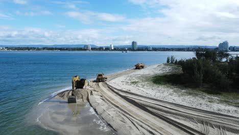 unique drone view of heavy machinery working on a coastal sand replenishment project close to a urban city sprawl