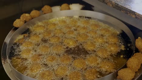 hermosa vista de las piezas de falafet fritas con aceite en una olla grande en la cocina