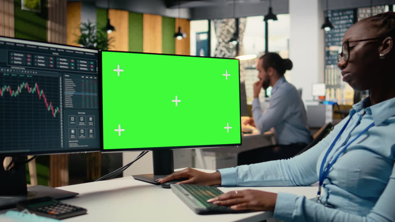 Day trader in brokerage office analyzes stock market charts on green screen PC