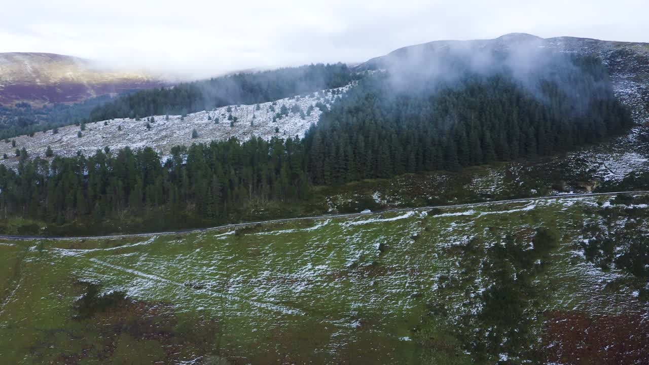 Journey Through Wicklow: Aerial Tracking of a Gray Car Amidst Misty Mountains and Snow-Covered Forests