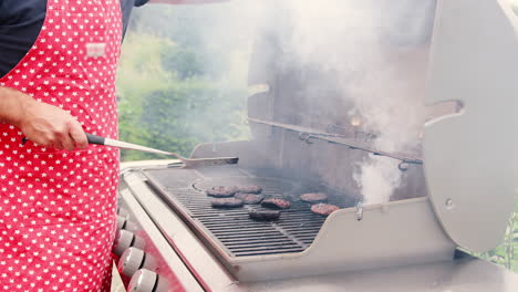 mature man burning burgers on outdoor barbecue