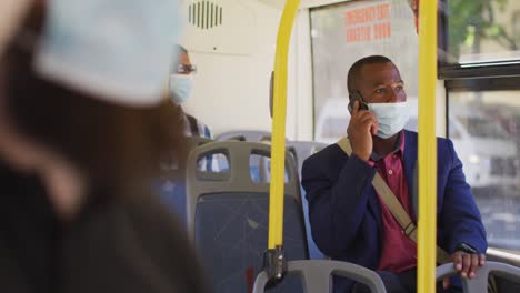 hombre afroamericano en la ciudad con cara, usando un teléfono inteligente en el autobús