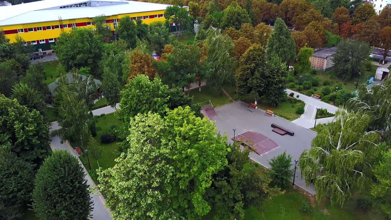 Wind blowing hard and shaking trees in the city park. Big fountain in the city garden. Aerial view.
