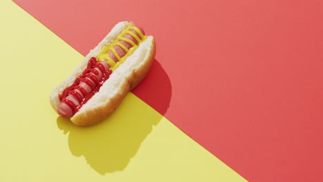 video de un perrito caliente con mostaza y ketchup en una superficie amarilla y roja
