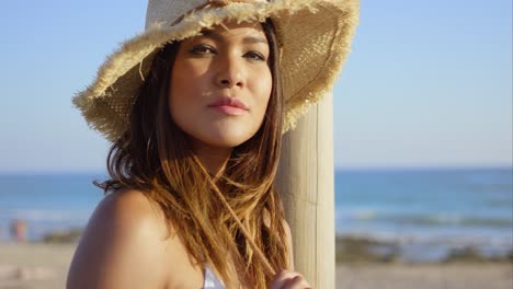 belleza seria con sombrero de paja y bikini blanco
