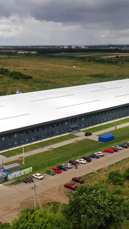 exterior of newly built factory. view from the air on a modern manufacturing construction in the countryside in summer. aerial view. motion camera forward. vertical video