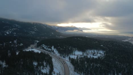 sunrise warm light illumines cariboo highway 95 surrounded by majestic cloud-covered mountains: stunning aerial reveal shot with panoramic view