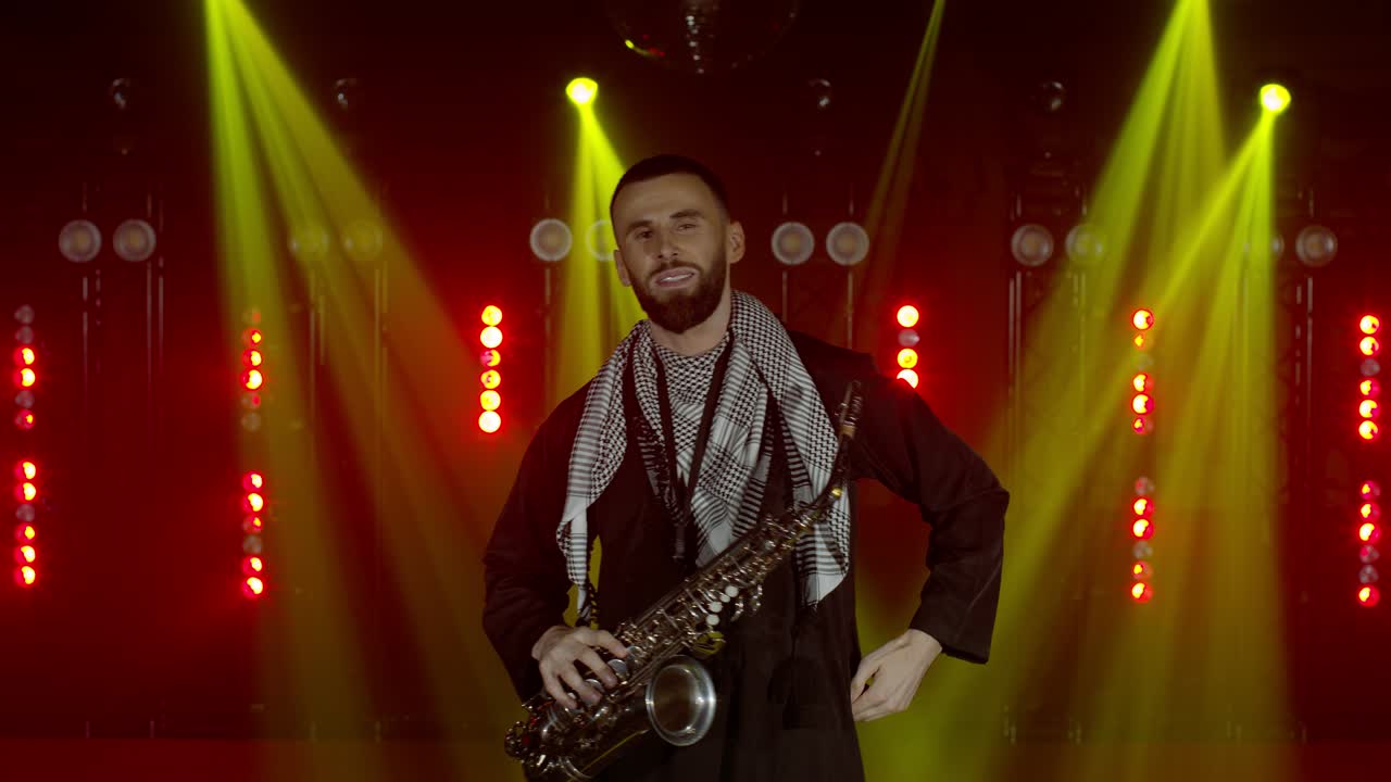 actuación en vivo del saxofonista hombre con saxofón, bailando en el escenario del músico de concierto con luces