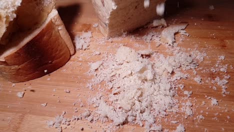 dry-full-grain-bread-loaf-crumbs-falling-in-slow-motion-on-the-cutting-board,-will-be-used-for-other-baking-recipes-in-kitchen