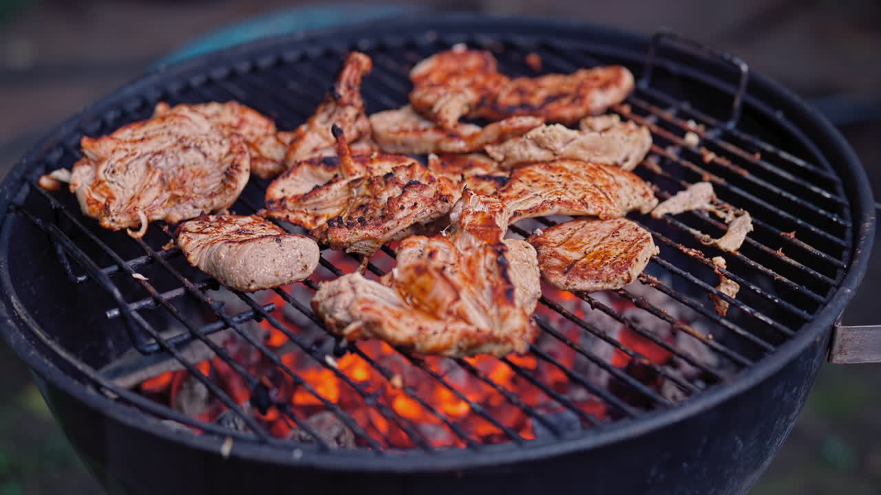 Una ripresa d'effetto di pollo che cuoce lentamente su braci rosse vivaci su una griglia usurata e ben utilizzata, con segni di grigliatura, texture a griglia aperta e il fascino autentico di un vero barbecue casalingo.