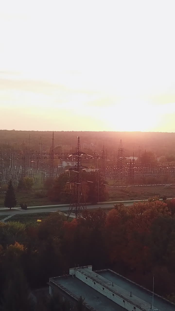 view of the site with high-voltage lines on the background of the road and trees at sunset. Camera motion forward. Aerial view Vertical video