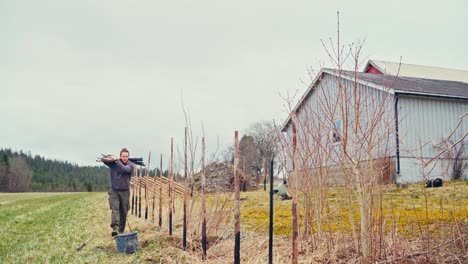 male constructing traditional norwegian fence (skigard) - wide shot