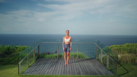 beautiful young woman in sportswear performing namaste greeting towards camera