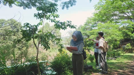asian muslim girl student in hijab learning and exploring nature with magnifying glass