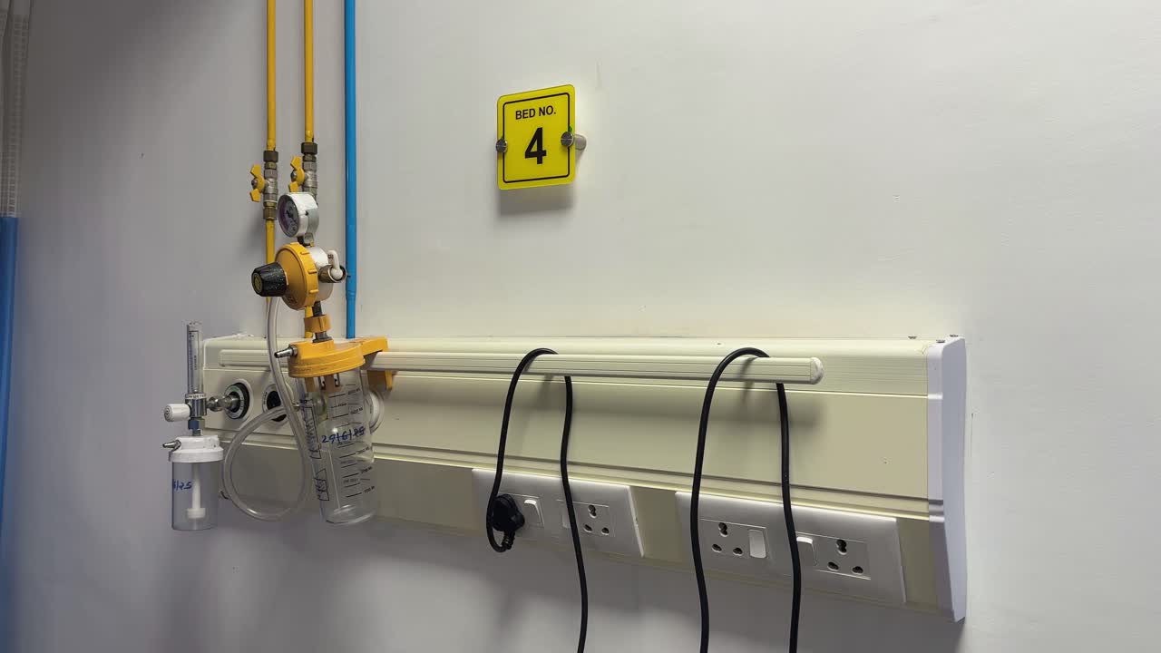 jib or crane shot of a hospital bed head panel in an ICU showing the integrated medical gas outlets, specifically oxygen and vacuum, along with electrical outlets