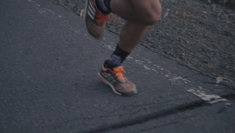 close up shot of professional runners feet and legs running on paved road in slow motion at dusk shot in hd