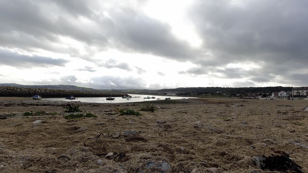 Overcast stormy clouds passing above British seaside resort town sandy beach timelapse