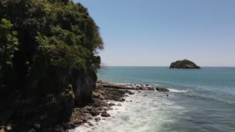 Drone-view-flying-away-of-Pacific-tropical-beach-Manuel-Antonio,-Costa-Rica