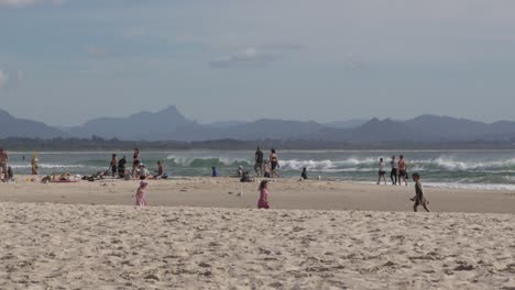 sandy beach shore ocean sea waves, people group walking australia byron bay