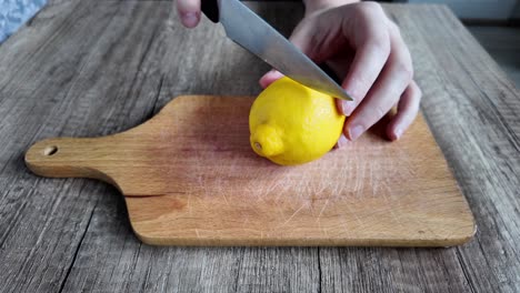 Ein-Mann-Schneidet-Eine-Gelbe-Zitrone-Mit-Einem-Messer-Auf-Einem-Tisch