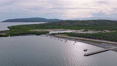 Toma-Ascendente-De-Drones-De-Barcos-Anclados-En-Playa-Tortuguero-Y-Montañas-Al-Fondo