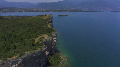 Toma-Aérea-Acercándose-A-Los-Acantilados-De-Manerba-En-El-Lago-Di-Garda-En-Un-Día-Soleado