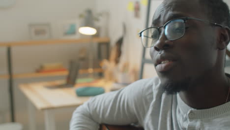 african american man playing guitar and singing at home