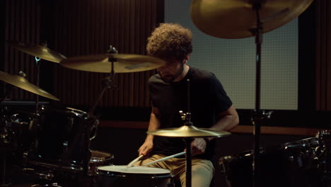 un baterista sombrío lanzando palos de batería en el estudio, un artista molesto saliendo de la sala de conciertos.