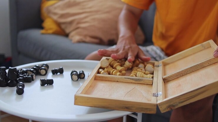 Close-up of hands storing chess pieces inside wooden case