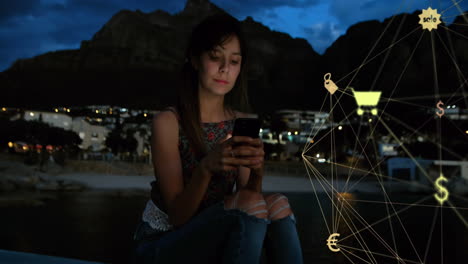globe of digital icons spinning against caucasian using smartphone outdoors at night