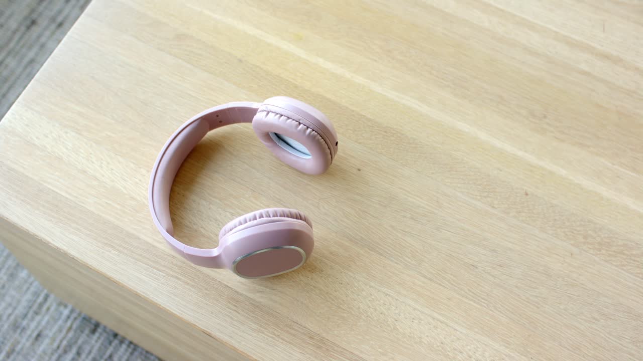La camera sta iniziando a registrare, catturando una ripresa dall'alto di cuffie wireless rosa su un tavolo per l'esposizione
