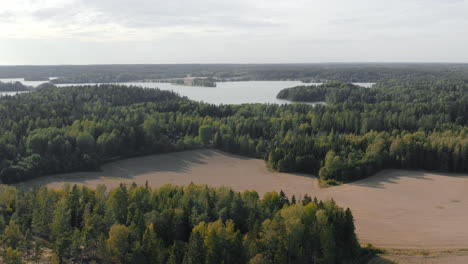 Aéreo,-En-Ascenso,-Toma-De-Drones-Con-Vistas,-Bosques,-Campos-Y-Un-Lago,-En-Un-Día-De-Verano-Brumoso-Y-Parcialmente-Soleado,-En-Kirkkonummi,-Uusimaa,-Finlandia